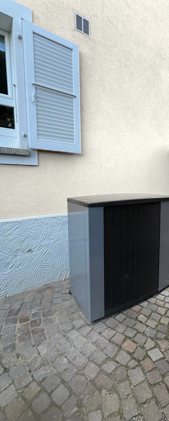 Pompe à chaleur air/eau monobloc posée contre la façade, sur pavés